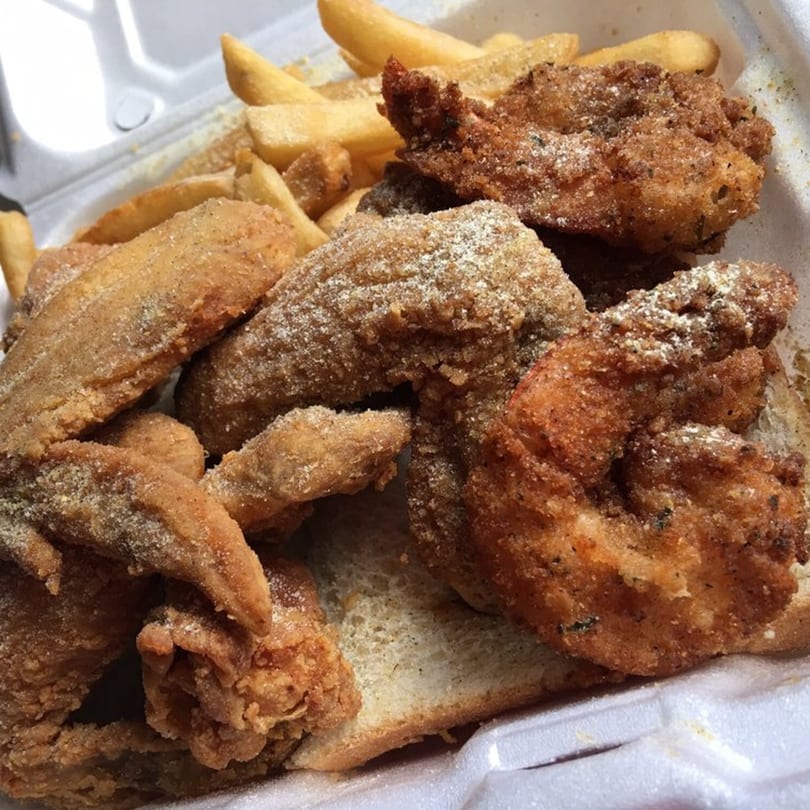 A takeout container filled with crispy fried chicken wings and golden french fries from Chicago Munchies.
