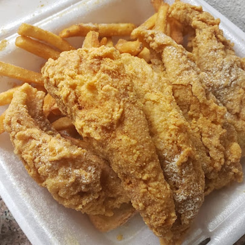 Golden-brown fried fish fillets and french fries in a white takeout container from Chicago Munchies.