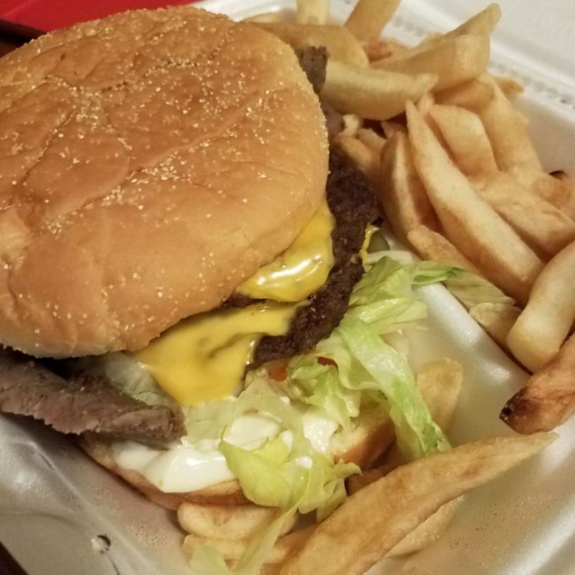 Cheeseburger with lettuce, mayonnaise, and fries in a white takeout container from Chicago Munchies.